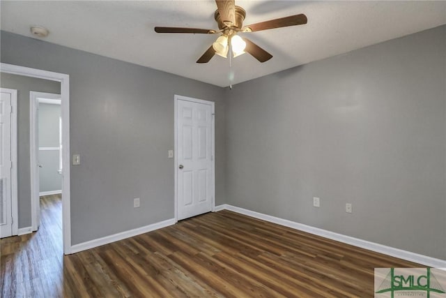 unfurnished room with dark wood-style floors, baseboards, and a ceiling fan