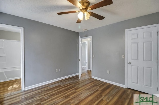 unfurnished bedroom with a ceiling fan, dark wood finished floors, a textured ceiling, and baseboards