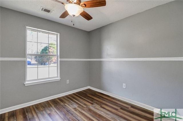 empty room with baseboards, visible vents, a ceiling fan, dark wood-style flooring, and a textured ceiling