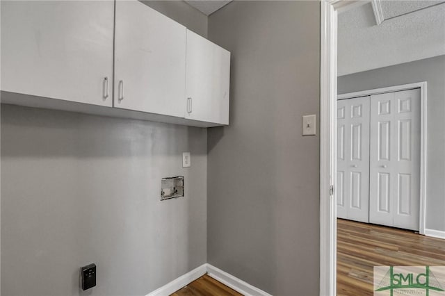 laundry area with washer hookup, cabinet space, a textured ceiling, wood finished floors, and baseboards