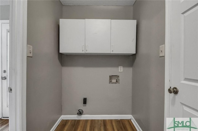 clothes washing area with hookup for a washing machine, cabinet space, dark wood finished floors, and baseboards