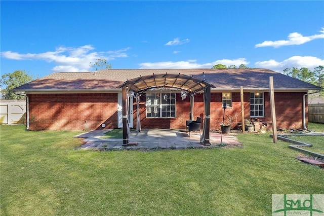 rear view of property featuring a yard, a patio, and brick siding