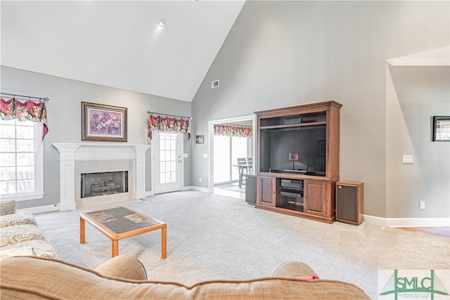 carpeted living room with high vaulted ceiling, a tile fireplace, visible vents, and baseboards