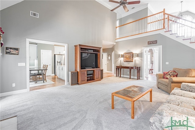 living area with visible vents, ceiling fan, light carpet, and baseboards