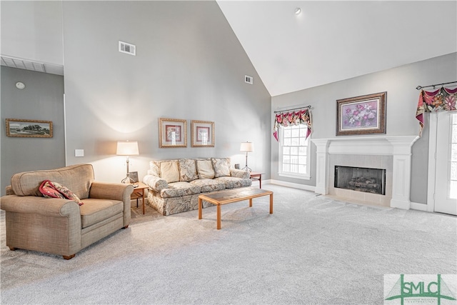 carpeted living room with high vaulted ceiling, baseboards, a fireplace, and visible vents