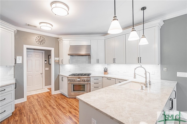 kitchen featuring wall oven, visible vents, a peninsula, ventilation hood, and a sink