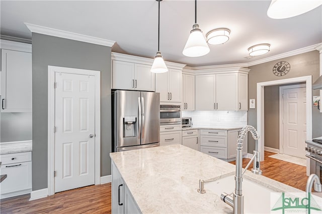 kitchen featuring appliances with stainless steel finishes, white cabinets, ornamental molding, and tasteful backsplash