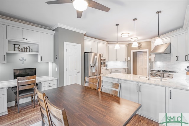 kitchen featuring tasteful backsplash, stainless steel fridge, crown molding, and wall chimney range hood