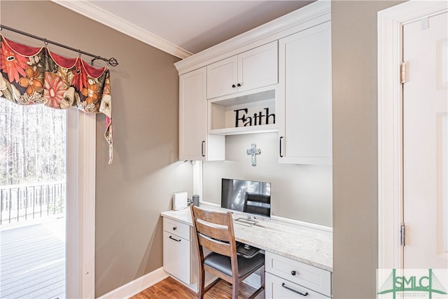 home office with baseboards, ornamental molding, light wood-style flooring, and built in study area