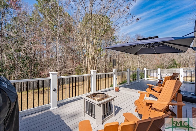 wooden deck featuring an outdoor fire pit and area for grilling