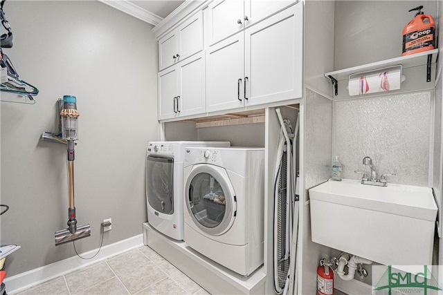 laundry room featuring washer and clothes dryer, light tile patterned floors, cabinet space, a sink, and baseboards