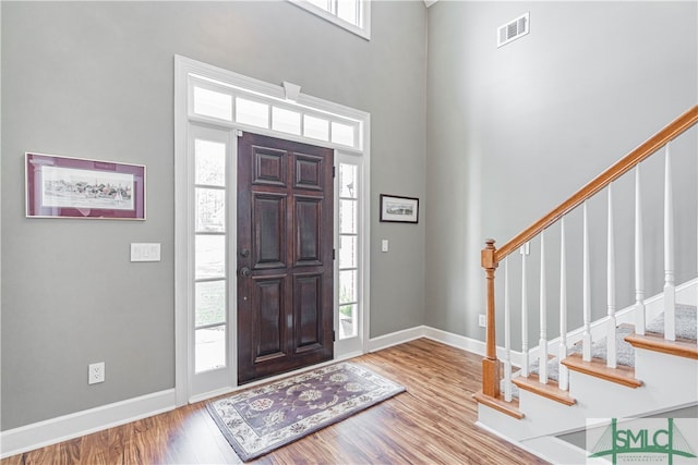 foyer entrance with stairs, wood finished floors, visible vents, and baseboards