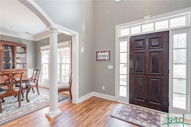 entryway with ornamental molding, a healthy amount of sunlight, light wood-type flooring, and ornate columns