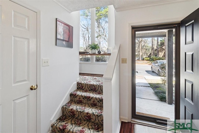 entryway with ornamental molding, stairway, plenty of natural light, and wood finished floors