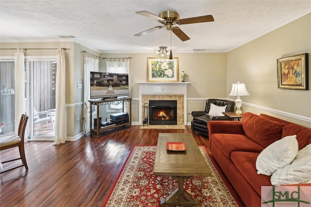 living area with ornamental molding, visible vents, a textured ceiling, and wood finished floors