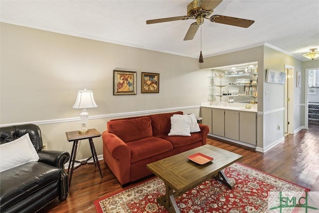 living area featuring a ceiling fan, crown molding, baseboards, and dark wood-type flooring