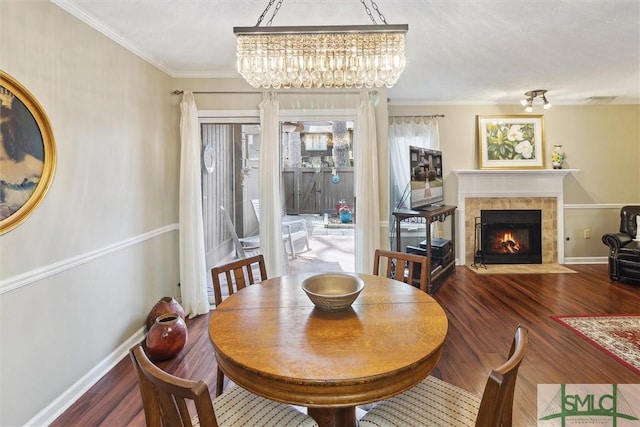 dining area featuring crown molding, a fireplace, baseboards, and wood finished floors