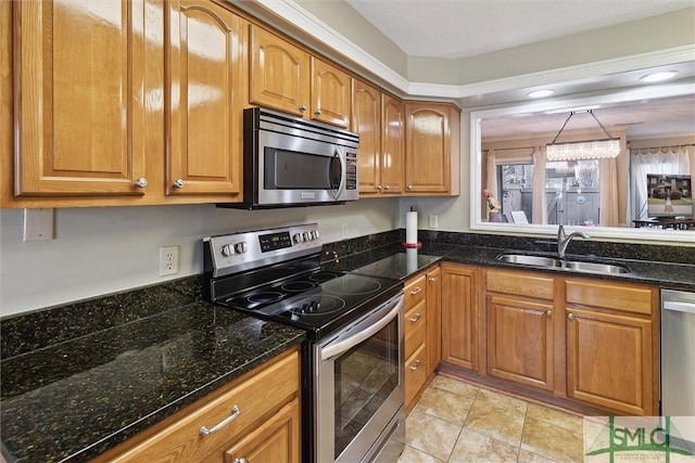 kitchen with appliances with stainless steel finishes, brown cabinetry, a sink, and dark stone countertops