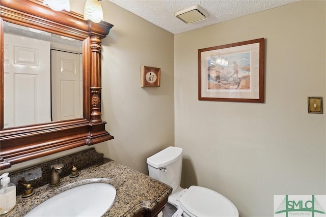 bathroom with visible vents, a textured ceiling, toilet, and vanity