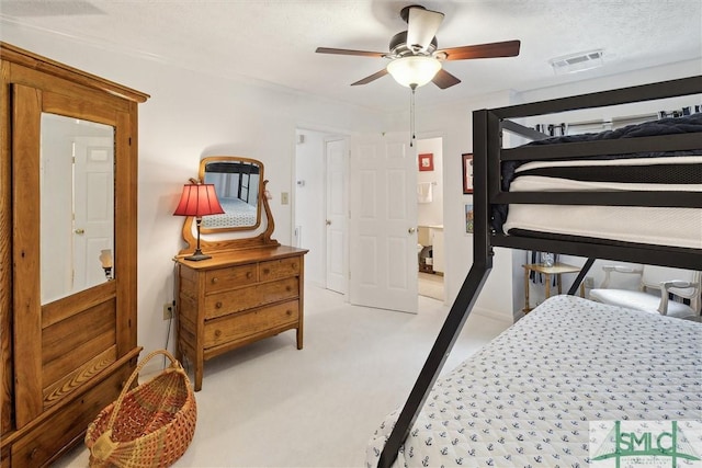 bedroom with a textured ceiling, a ceiling fan, visible vents, and light colored carpet