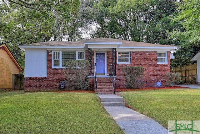 view of front of house featuring a front yard, brick siding, and fence