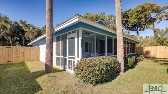 view of side of property featuring a sunroom, a fenced backyard, and a yard