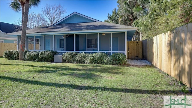 view of front of property featuring a sunroom, a fenced backyard, a front lawn, and central AC