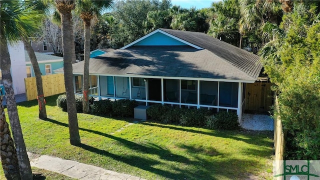 back of house featuring a lawn, fence, and a sunroom