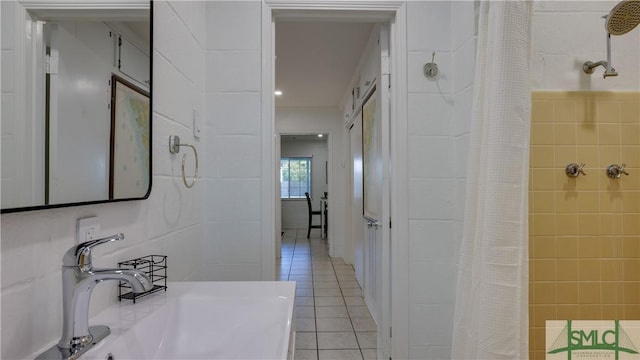 bathroom featuring tile patterned flooring, tile walls, a sink, and tiled shower