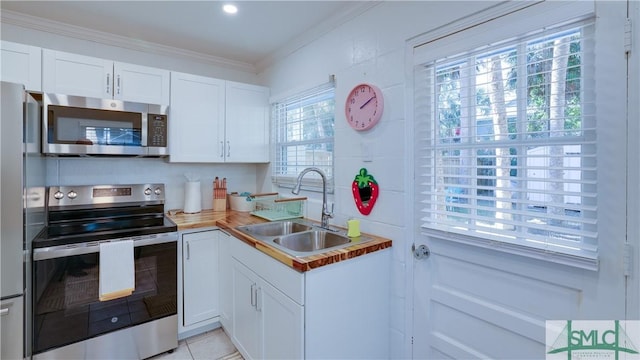 kitchen featuring white cabinets, ornamental molding, stainless steel appliances, light countertops, and a sink