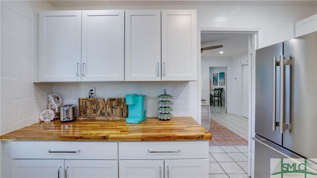 bar featuring high end fridge and light tile patterned floors