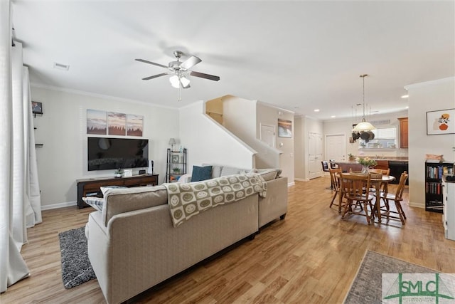 living area with visible vents, crown molding, light wood-style flooring, and baseboards