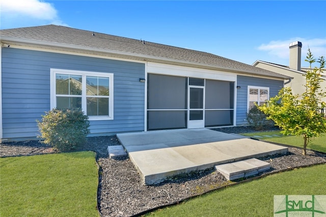 back of property featuring a yard, a sunroom, roof with shingles, and a patio