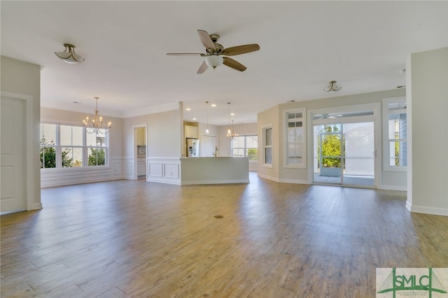 unfurnished living room featuring plenty of natural light, light wood finished floors, and ceiling fan with notable chandelier