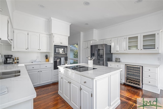 kitchen with light stone countertops, wine cooler, ornamental molding, black appliances, and a sink