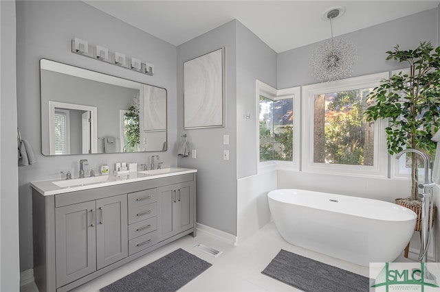 bathroom with double vanity, a soaking tub, baseboards, and a sink