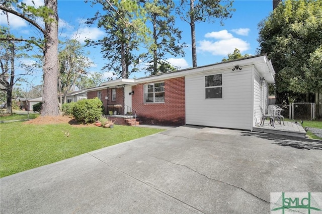 ranch-style house featuring concrete driveway, brick siding, fence, and a front lawn