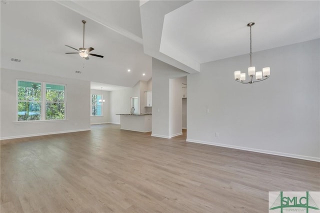 unfurnished living room with light wood finished floors, baseboards, visible vents, high vaulted ceiling, and ceiling fan with notable chandelier