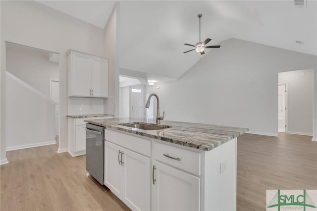 kitchen featuring stainless steel dishwasher, light stone counters, open floor plan, and a sink