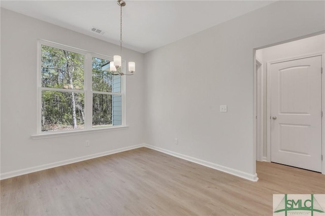 empty room featuring light wood finished floors, plenty of natural light, visible vents, and a chandelier