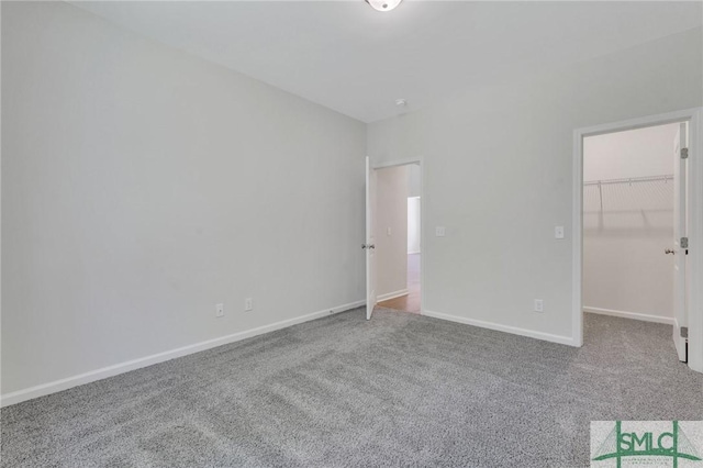 unfurnished bedroom featuring carpet floors, a walk in closet, and baseboards