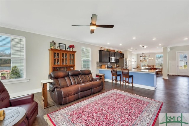 living area featuring recessed lighting, ceiling fan with notable chandelier, dark wood-style flooring, baseboards, and ornamental molding