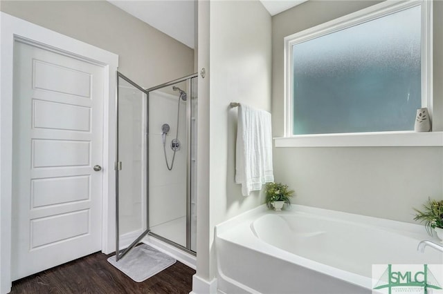 full bath featuring a garden tub, a shower stall, and wood finished floors