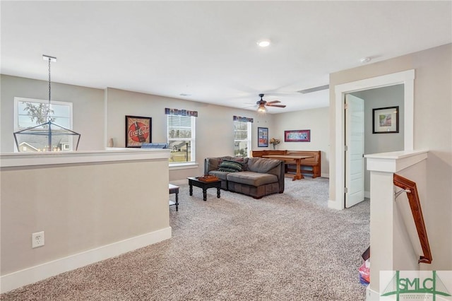 living room with ceiling fan with notable chandelier, carpet flooring, visible vents, and baseboards