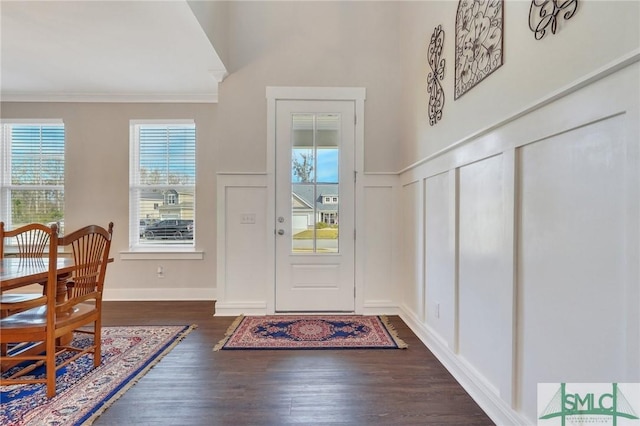 entrance foyer featuring ornamental molding, wainscoting, a decorative wall, and wood finished floors