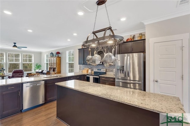 kitchen with visible vents, decorative backsplash, ornamental molding, a peninsula, and stainless steel appliances