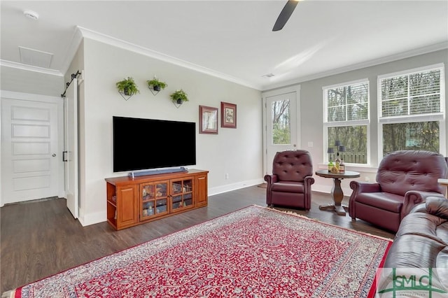 living room featuring ornamental molding, dark wood finished floors, baseboards, and a barn door