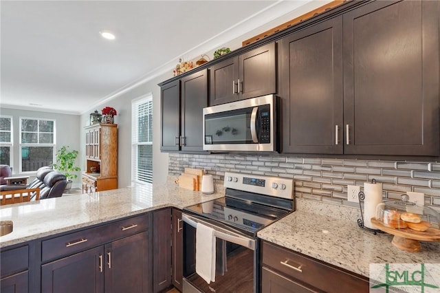 kitchen with stainless steel appliances, a wealth of natural light, backsplash, and dark brown cabinets