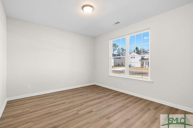 spare room with visible vents, baseboards, and wood finished floors