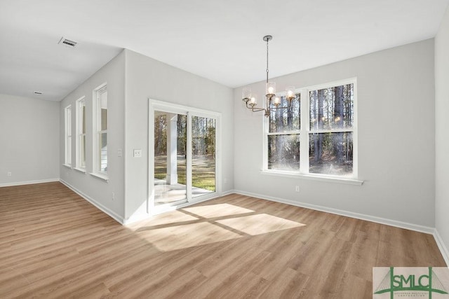 unfurnished dining area featuring a chandelier, visible vents, light wood-style flooring, and baseboards